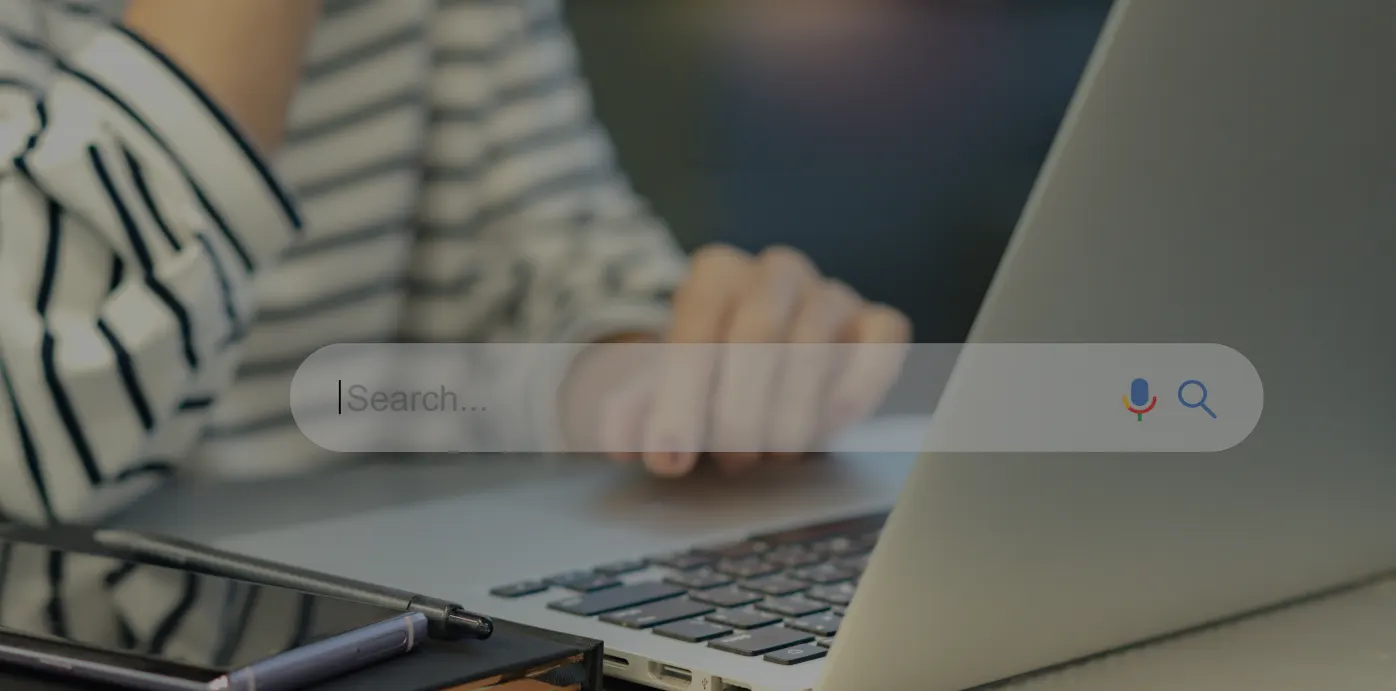 Person typing on a laptop keyboard while viewing the Google search bar and search results on the screen during keyword research.